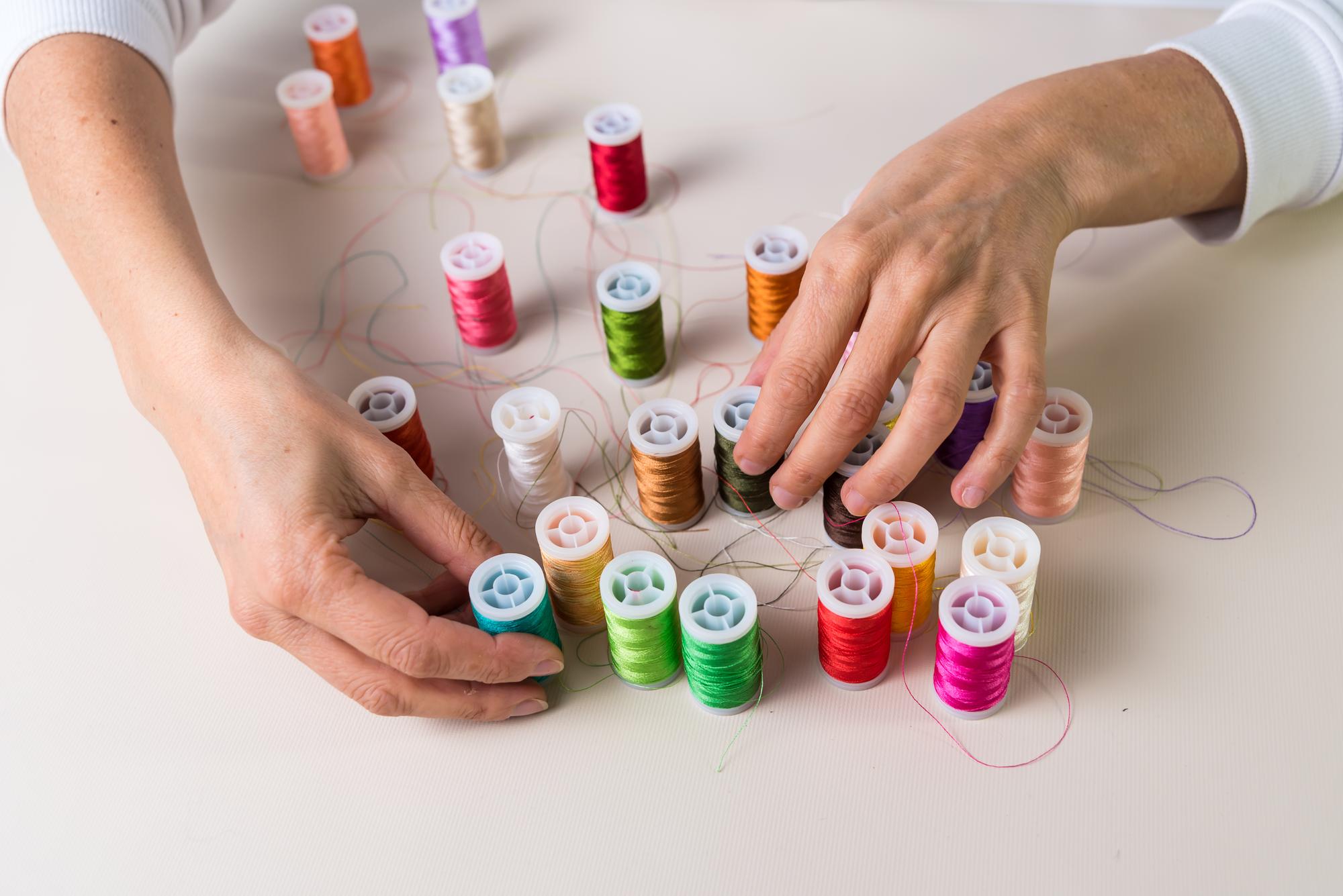 Hands arranging thread spools in studio